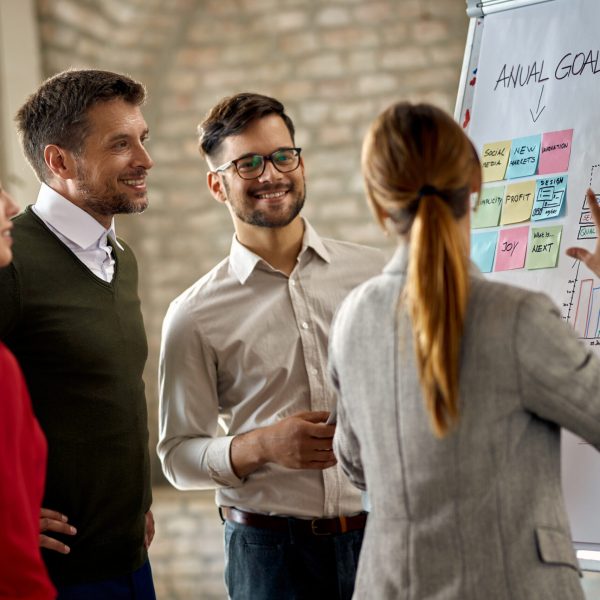 Happy business team cooperating while analyzing their business progress on whiteboard in the office.
